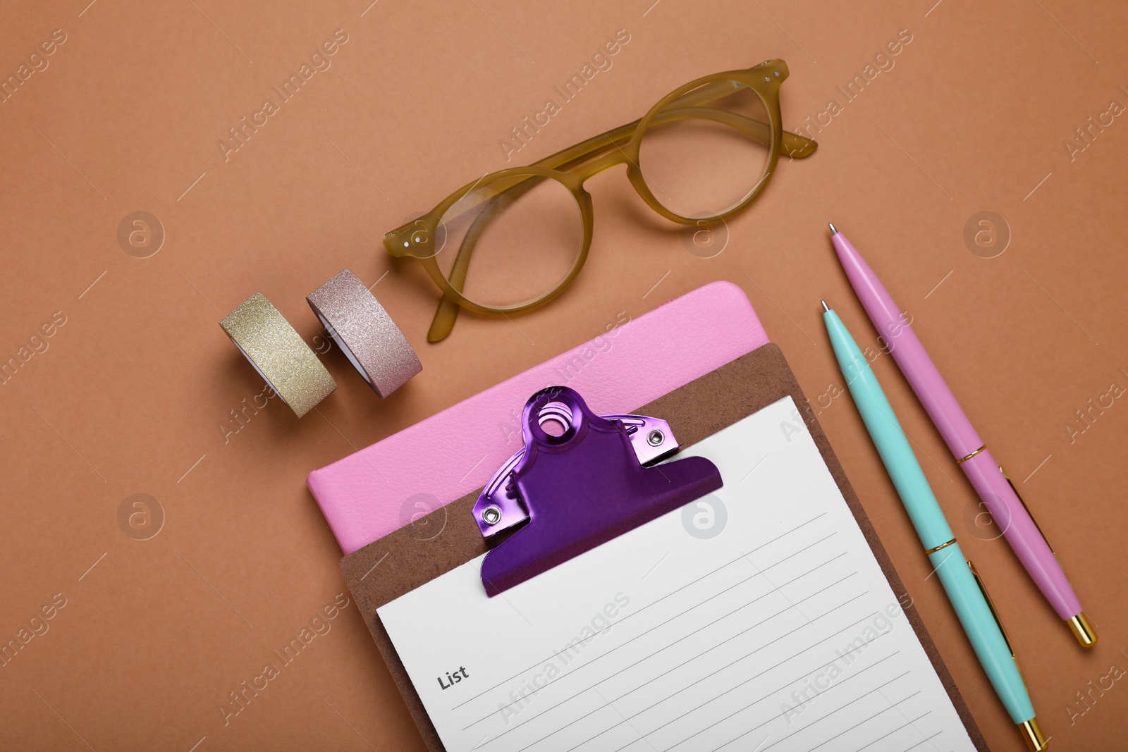 Photo of Clipboard with to do notes, pens, planner and glasses on brown background, flat lay