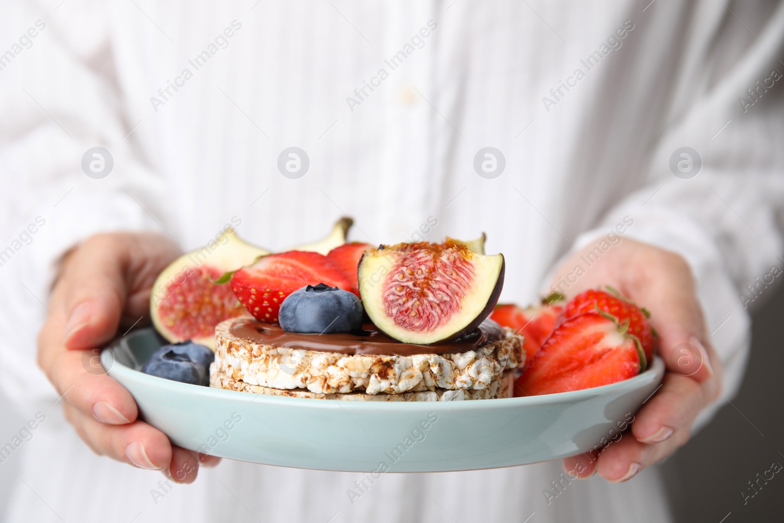 Photo of Woman holding plate with tasty crispbreads, fruits and sweet berries, closeup