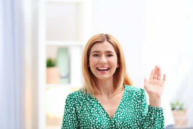 Photo of Beautiful woman using video chat for conversation indoors. Space for text