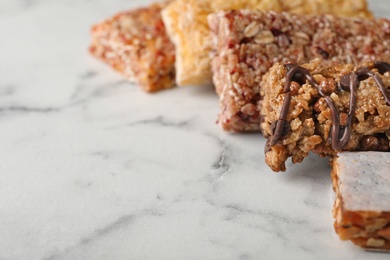 Photo of Tasty protein bars on marble table. Space for text