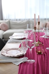 Beautiful table setting with candles and pink accent in dining room