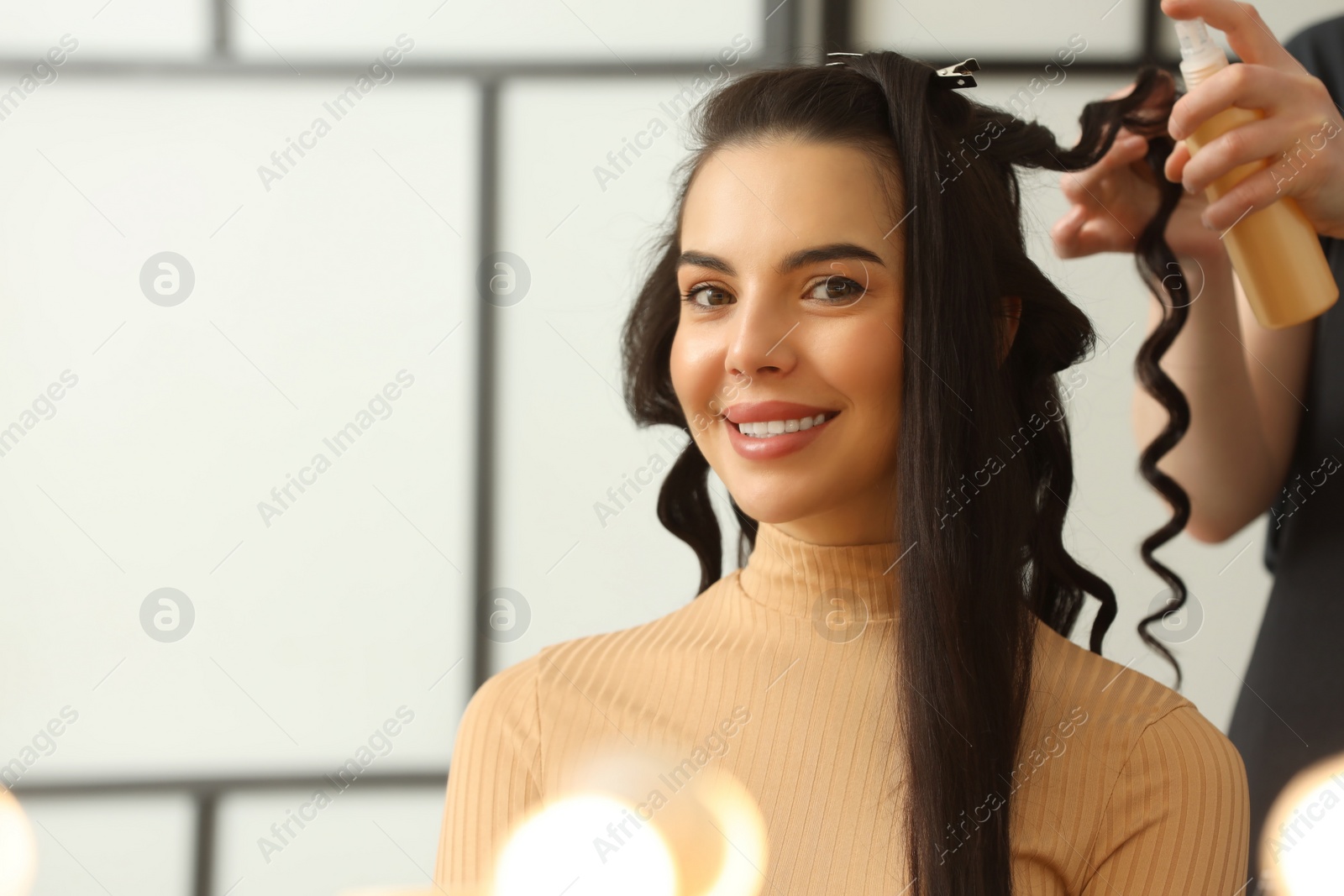 Photo of Hair styling. Professional hairdresser working with smiling client in salon, closeup. Space for text