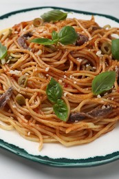 Photo of Delicious pasta with anchovies, tomato sauce and basil on white table, closeup