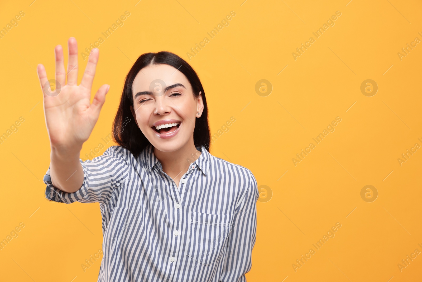 Photo of Happy woman giving high five on orange background, space for text