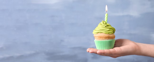 Image of Woman holding birthday cupcake on light blue background, closeup view with space for text. Banner design