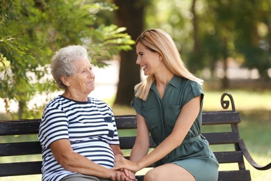 Woman with elderly mother on bench in park