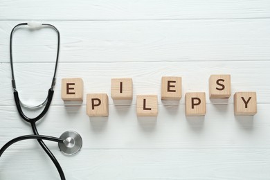 Photo of Wooden cubes with word Epilepsy and stethoscope on white table, flat lay