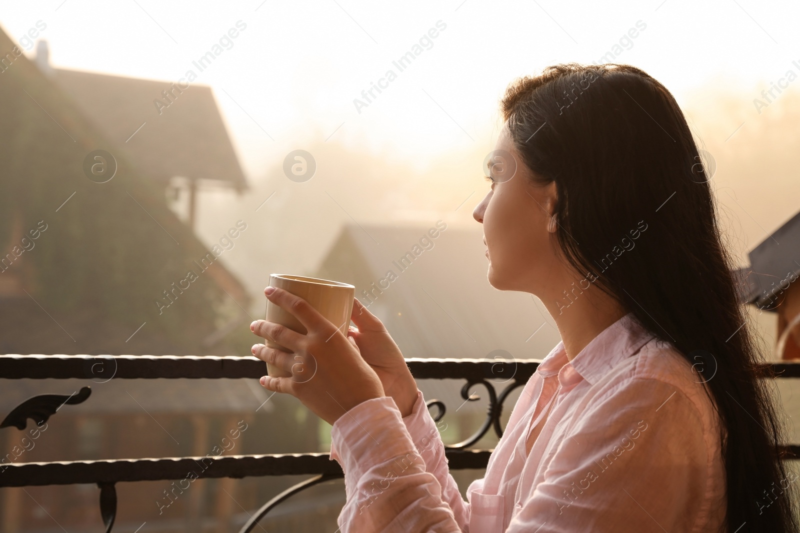 Photo of Young woman with cup of tea enjoying beautiful view in morning