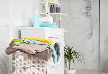 Wicker basket with laundry and washing machine in bathroom. Space for text