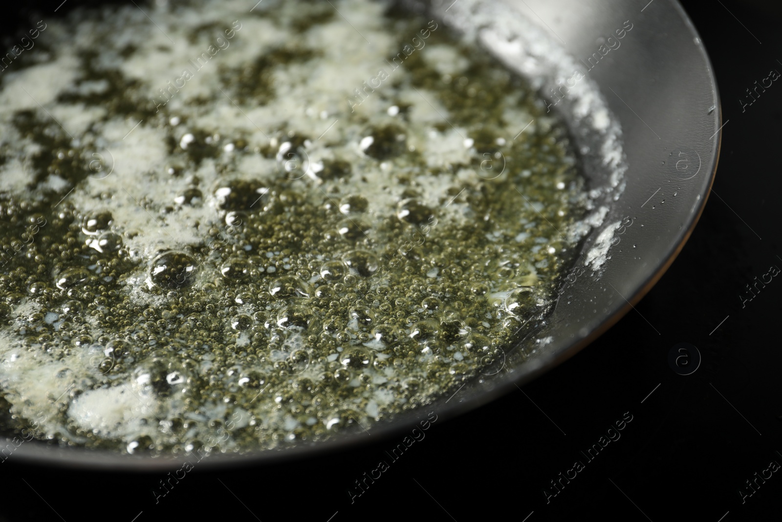 Photo of Melting butter in frying pan on black table, closeup