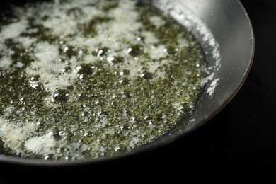 Photo of Melting butter in frying pan on black table, closeup