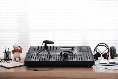 Photo of Professional audio equipment and stationery on wooden table in modern radio studio