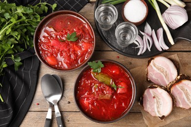Photo of Stylish brown clay bowls with Ukrainian borsch served on wooden table, flat lay