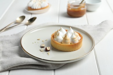 Photo of Tartlet with meringue on white wooden table. Delicious dessert