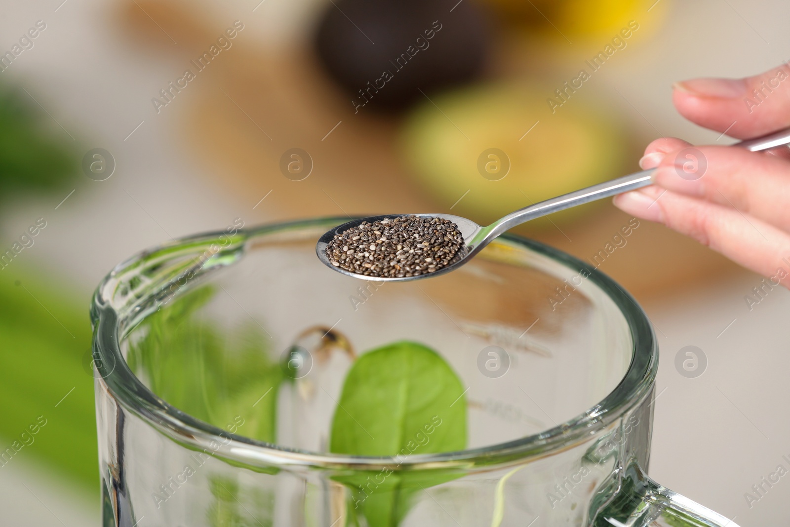 Photo of Woman adding chia seeds into blender with ingredients for green smoothie, closeup