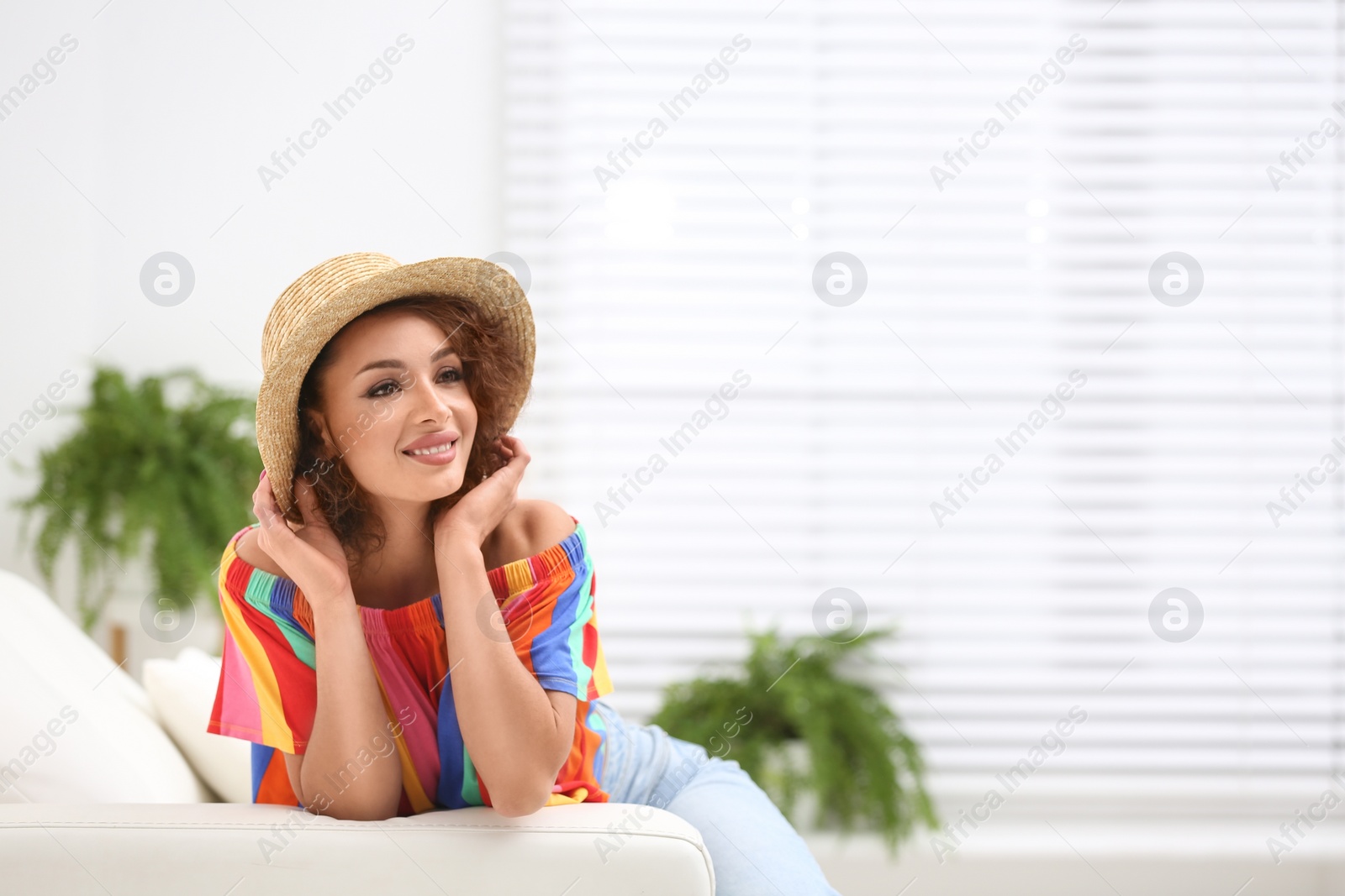 Photo of Beautiful woman in casual outfit on sofa indoors. Space for text