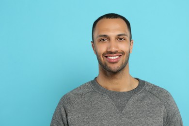 Portrait of handsome young man on light blue background, space for text