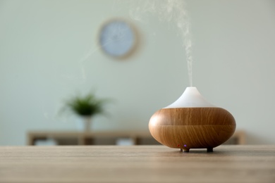 Photo of Modern aroma lamp on table against blurred background with space for text