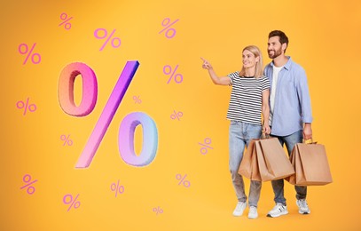 Discount offer. Couple with shopping bags looking at percent signs on orange background