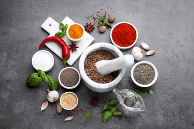 Photo of Mortar with different spices on grey table, flat lay
