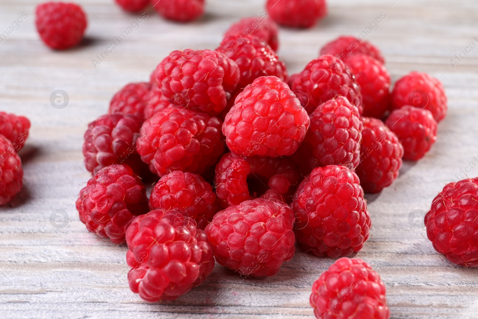 Photo of Tasty ripe raspberries on white wooden table, closeup