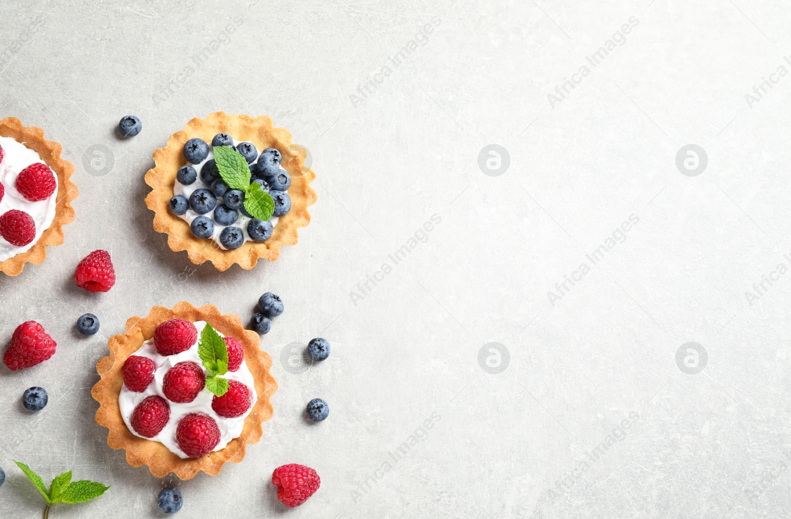 Photo of Delicious sweet pastries with berries on grey table, flat lay. Space for text