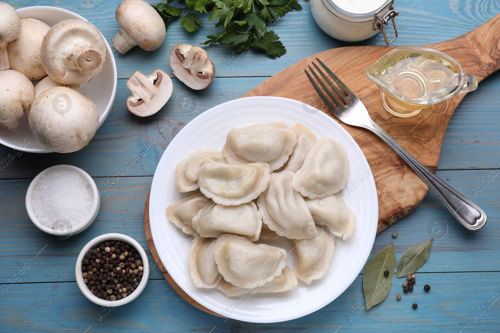 Photo of Delicious dumplings (varenyky) with potatoes served on light blue wooden table, flat lay