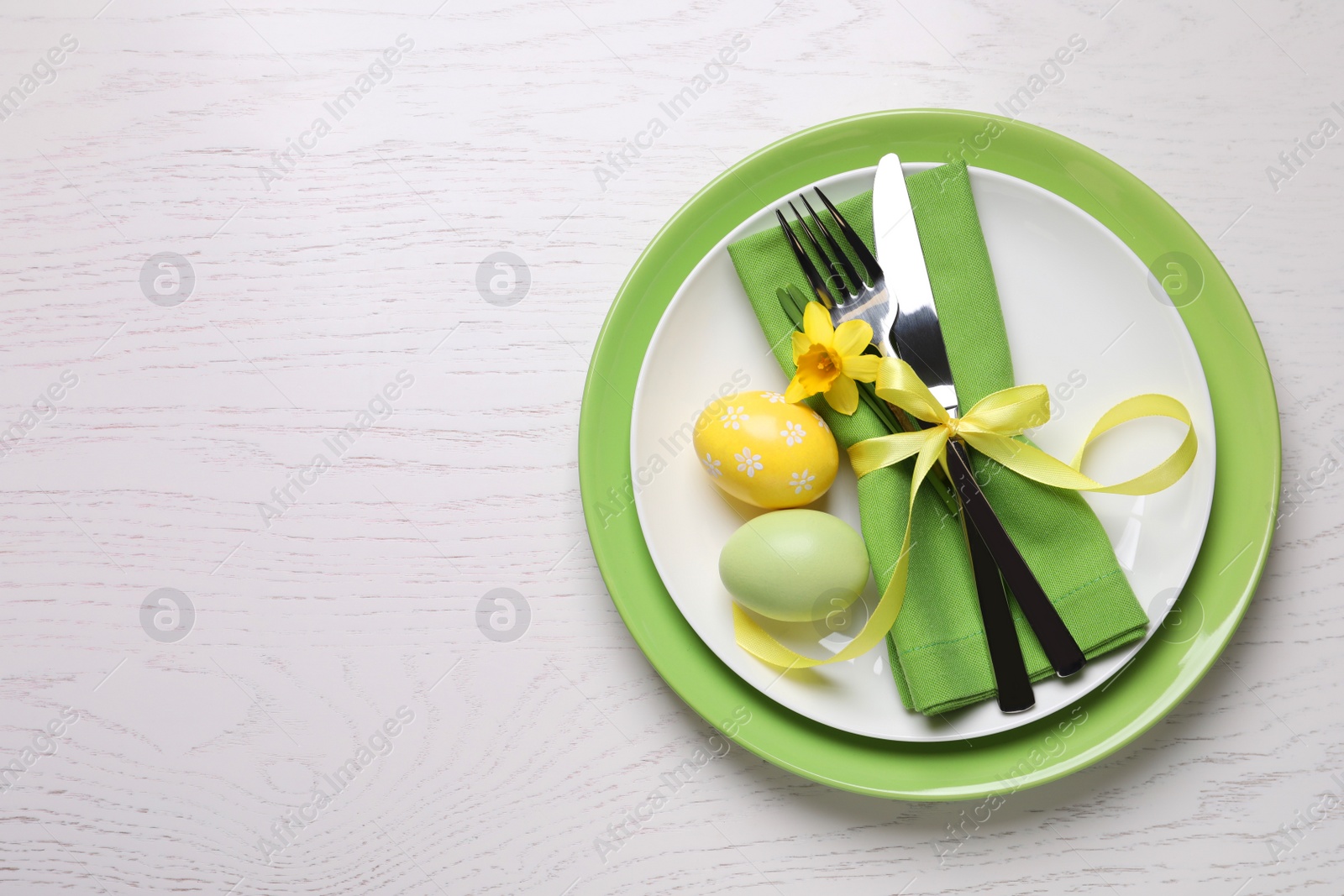 Photo of Festive Easter table setting with eggs on white wooden background, top view. Space for text