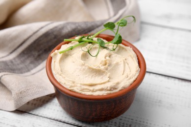 Bowl with delicious hummus on white wooden table, closeup