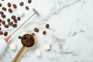 Photo of Milk frother wand, sugar cubes and coffee beans on white marble table, flat lay. Space for text