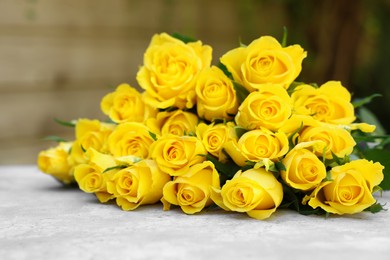 Beautiful bouquet of yellow roses on light table outdoors