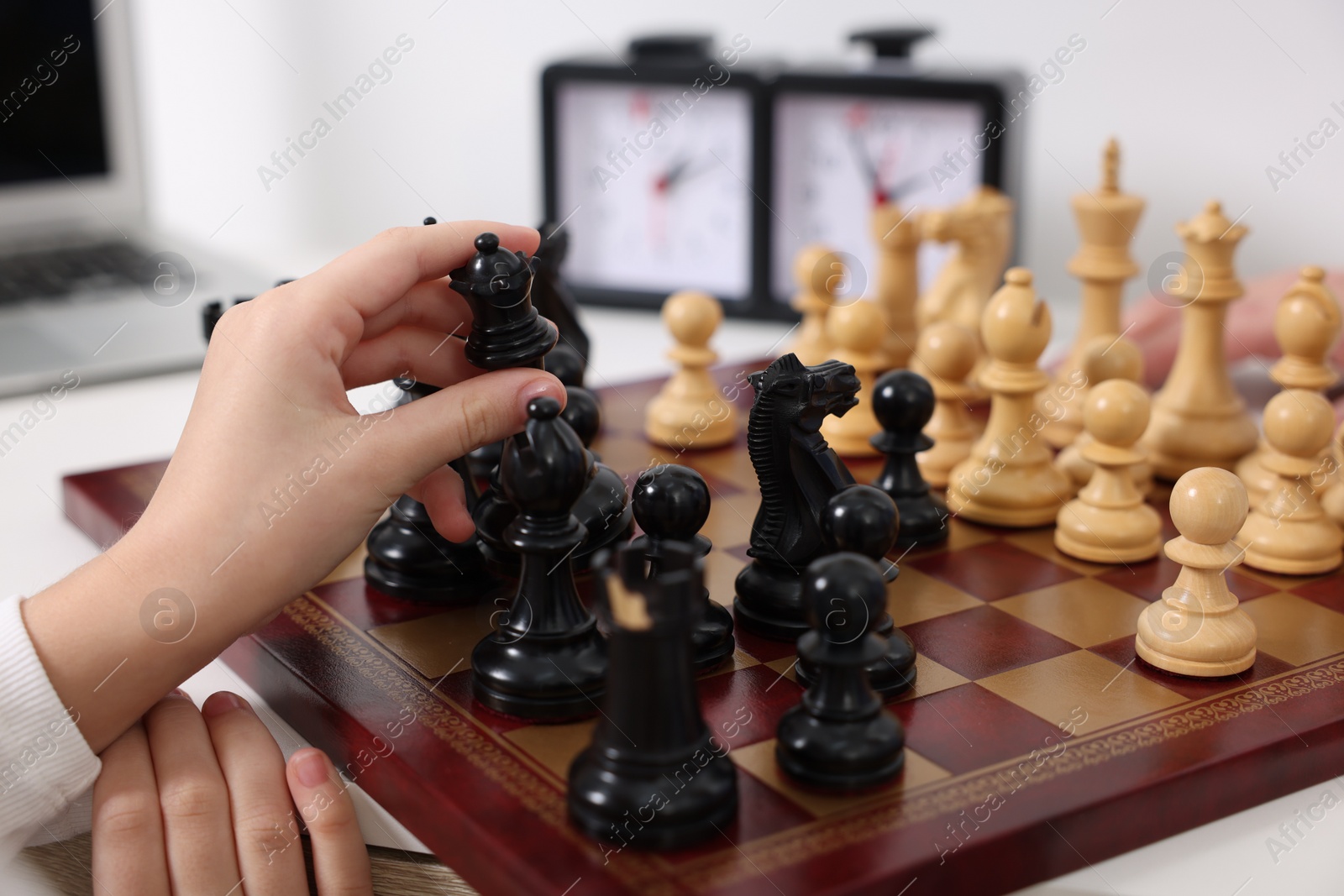 Photo of Little child playing chess at table indoors, closeup