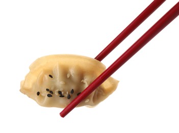 Photo of Chopsticks with delicious gyoza (asian dumpling) and sesame isolated on white