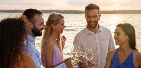 Image of Friends with glasses of wine having fun near river at summer party. Banner design