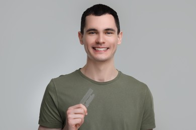 Photo of Young man with whitening strips on light grey background