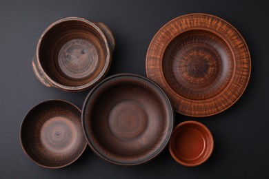 Photo of Bowls and plates on black background, flat lay