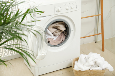 Modern washing machine with towels in bathroom