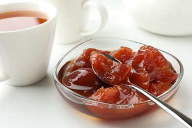 Photo of Quince jam in glass bowl served to tea on white table, closeup