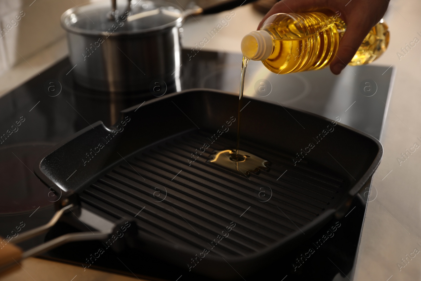 Photo of Man pouring cooking oil into frying pan in kitchen, closeup