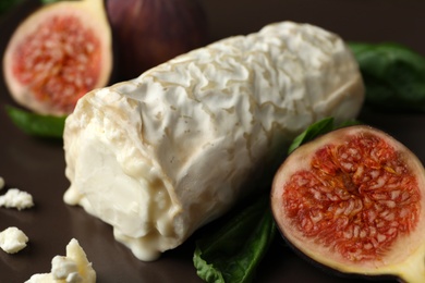 Photo of Delicious goat cheese with figs and basil on plate, closeup