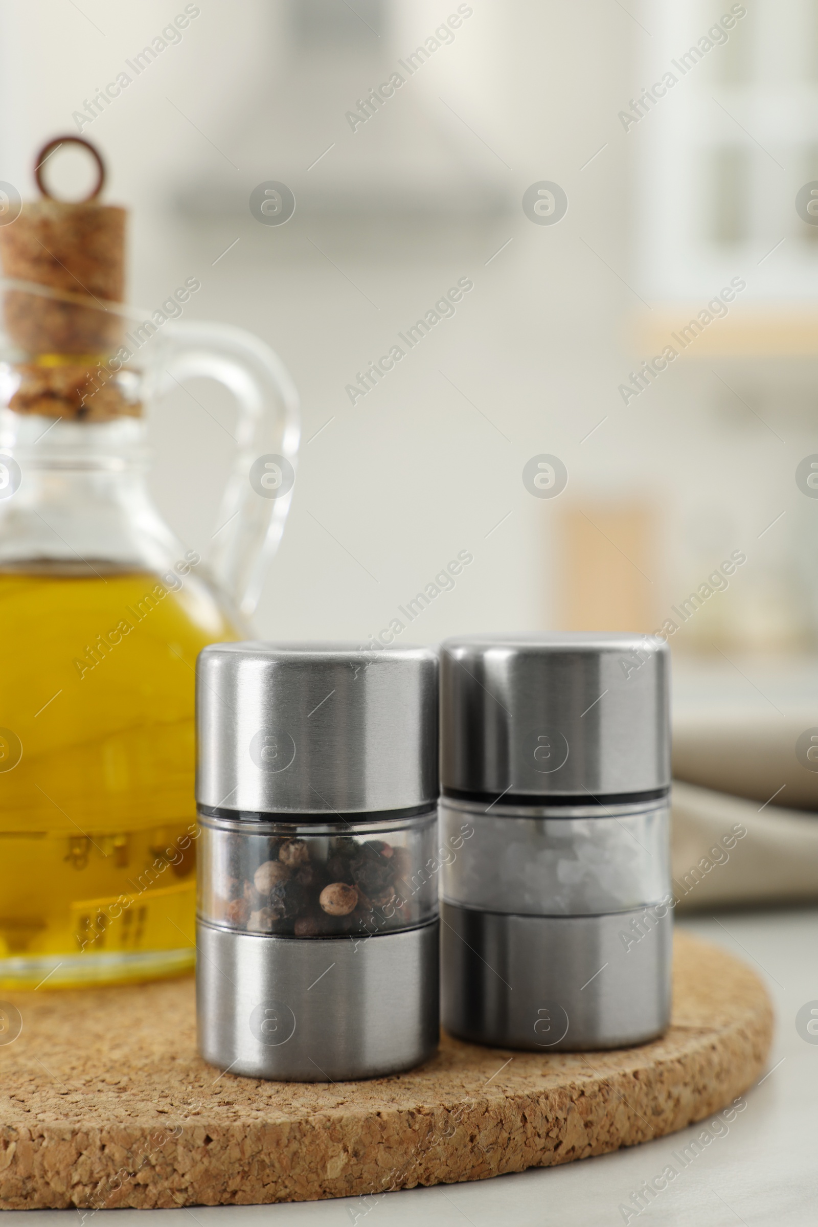 Photo of Salt and pepper mills with bottle of oil on table in kitchen