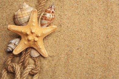 Photo of Beautiful sea star, shells and ropes on sand, flat lay. Space for text