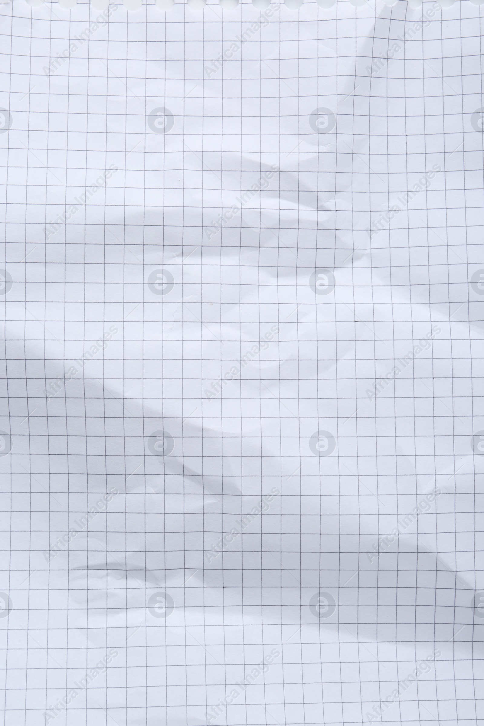 Photo of Crumpled checkered notebook sheet as background, top view