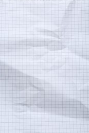 Crumpled checkered notebook sheet as background, top view