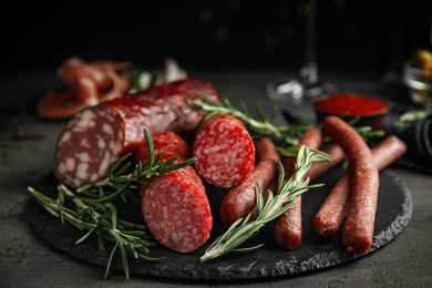 Photo of Different types of sausages with rosemary on grey table