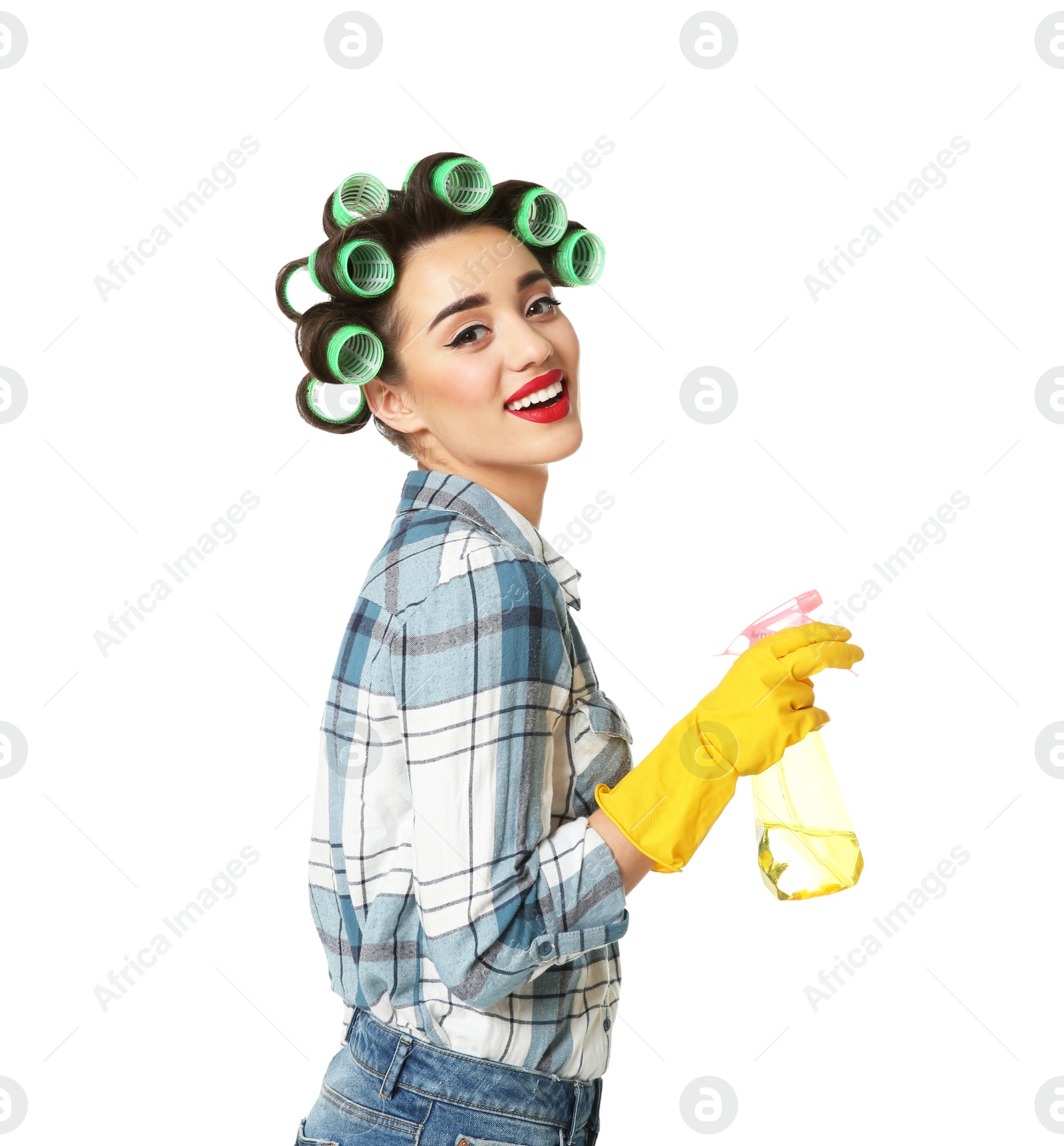 Photo of Funny young housewife with hair rollers holding detergent on white background