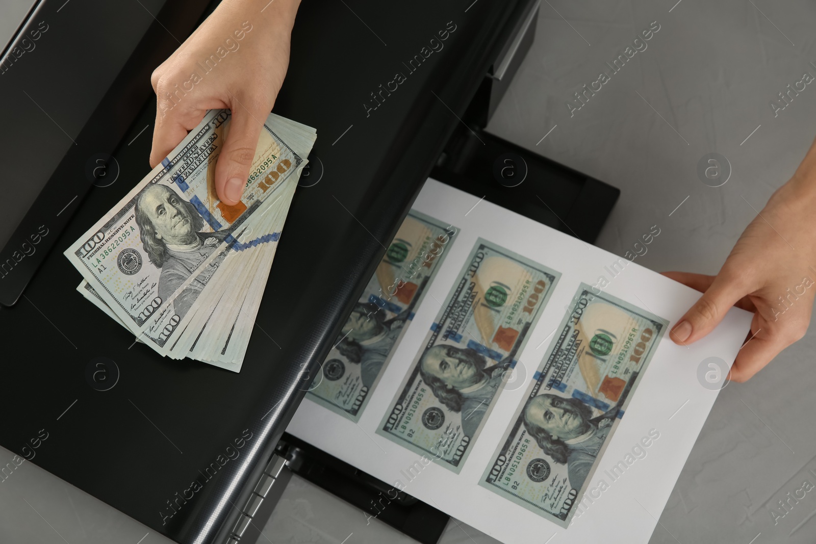 Photo of Counterfeiter printing dollar banknotes at grey table, top view. Fake money concept