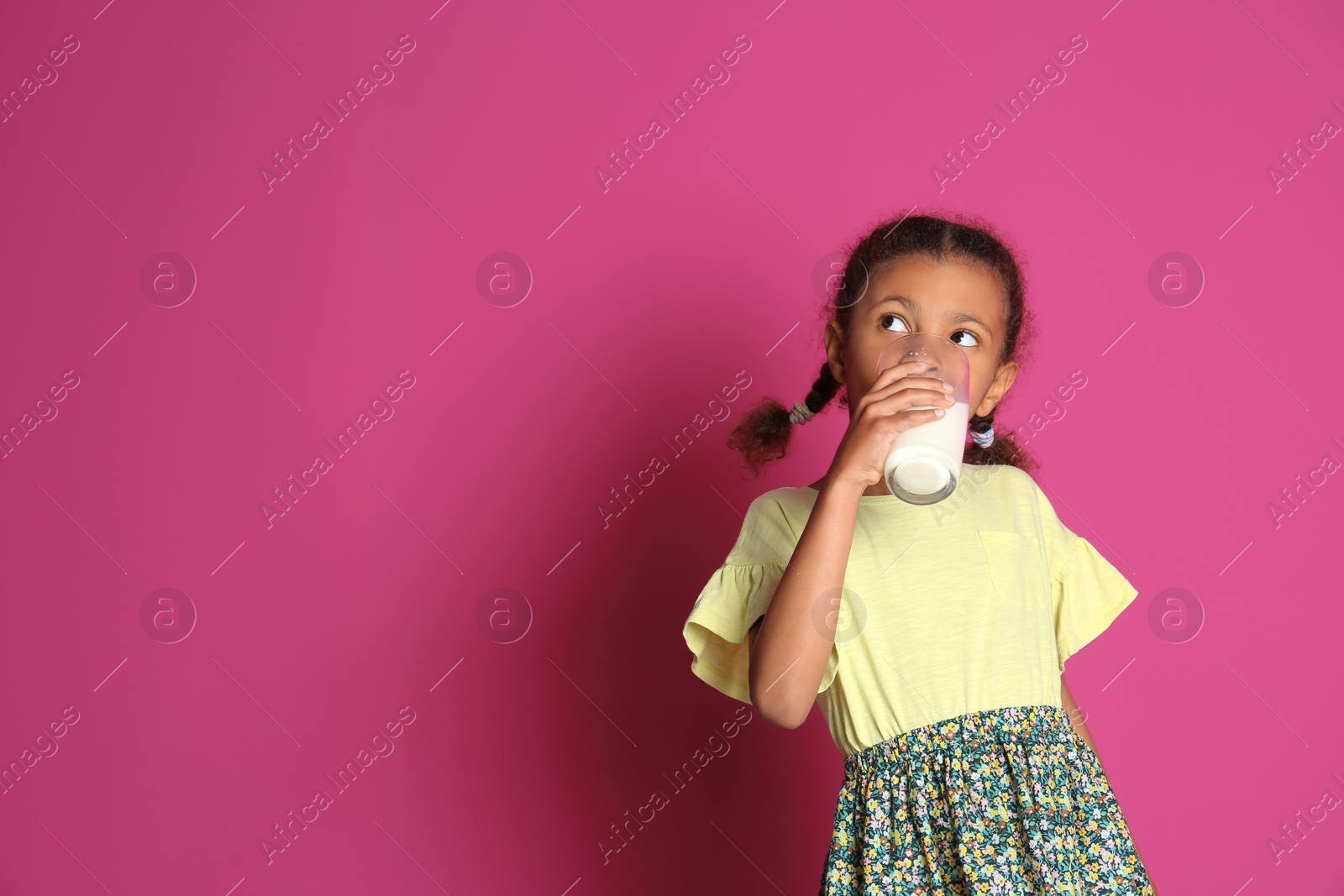 Photo of Adorable African-American girl with glass of milk on color background