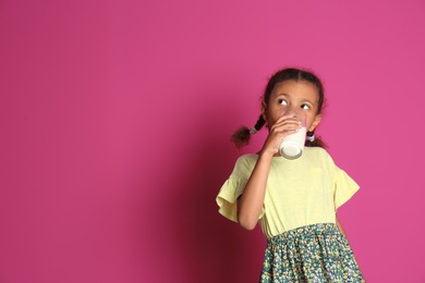 Photo of Adorable African-American girl with glass of milk on color background