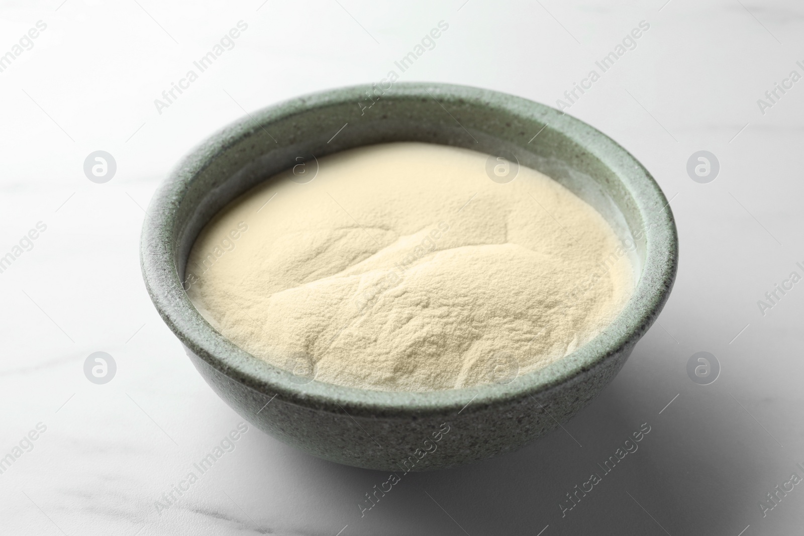 Photo of Bowl of agar-agar powder on white marble table